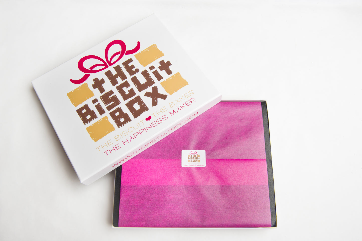 biscuit box packaging that shows branded lid and mini branded sticker. Pink tissue paper. shallow box that can fit through letterbox.