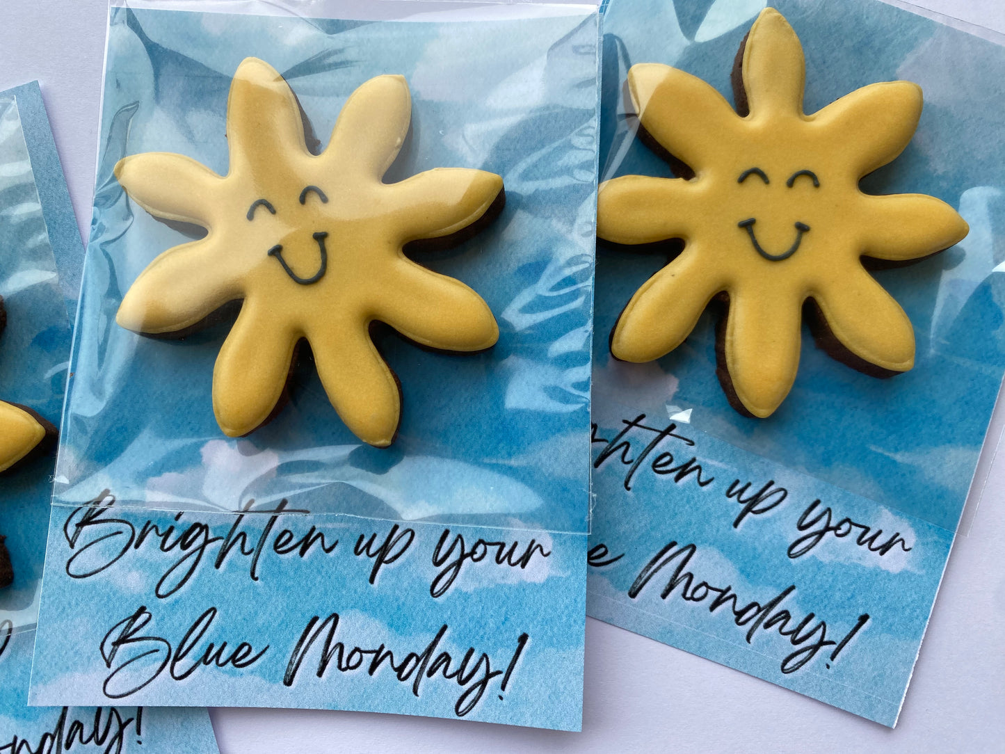 yellow sun cookie in cellophane on a blue sky background. Corporate gift for blue Monday. Sunshine biscuit to cheer up blue Monday. 