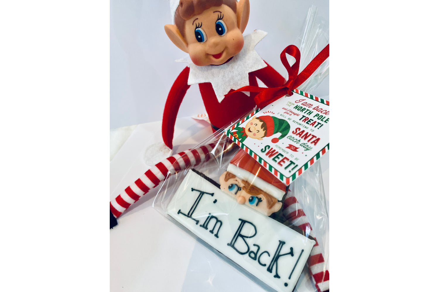 elf on the shelf biscuits to announce the elf is back. Iced biscuit that says I'm back in black icing with elf face either side.