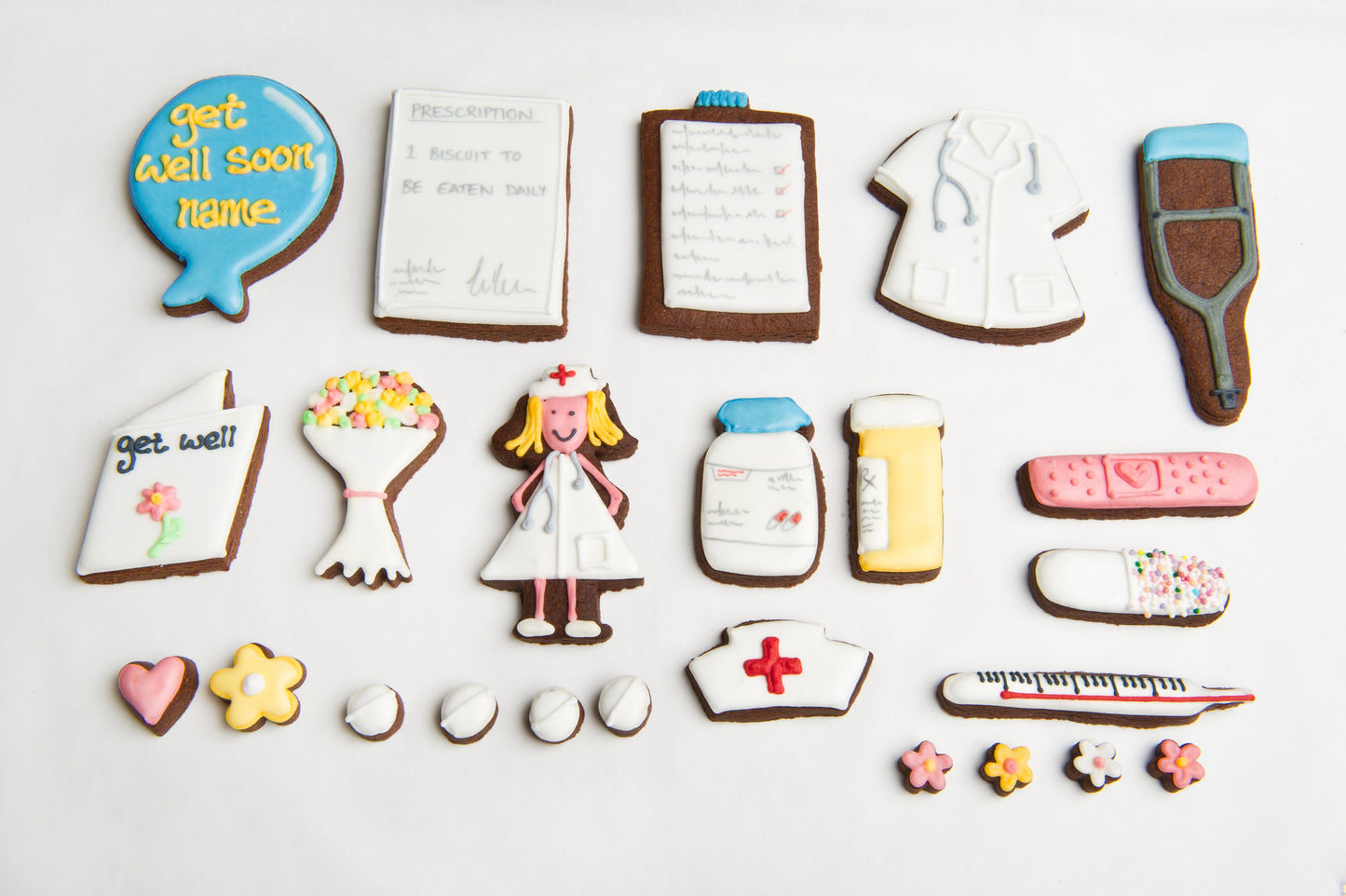 layout of the get well soon tin biscuits. nurse biscuit, doctors coat, prescription cookie.  plaster and pill pots hand iced luxury biscuits.