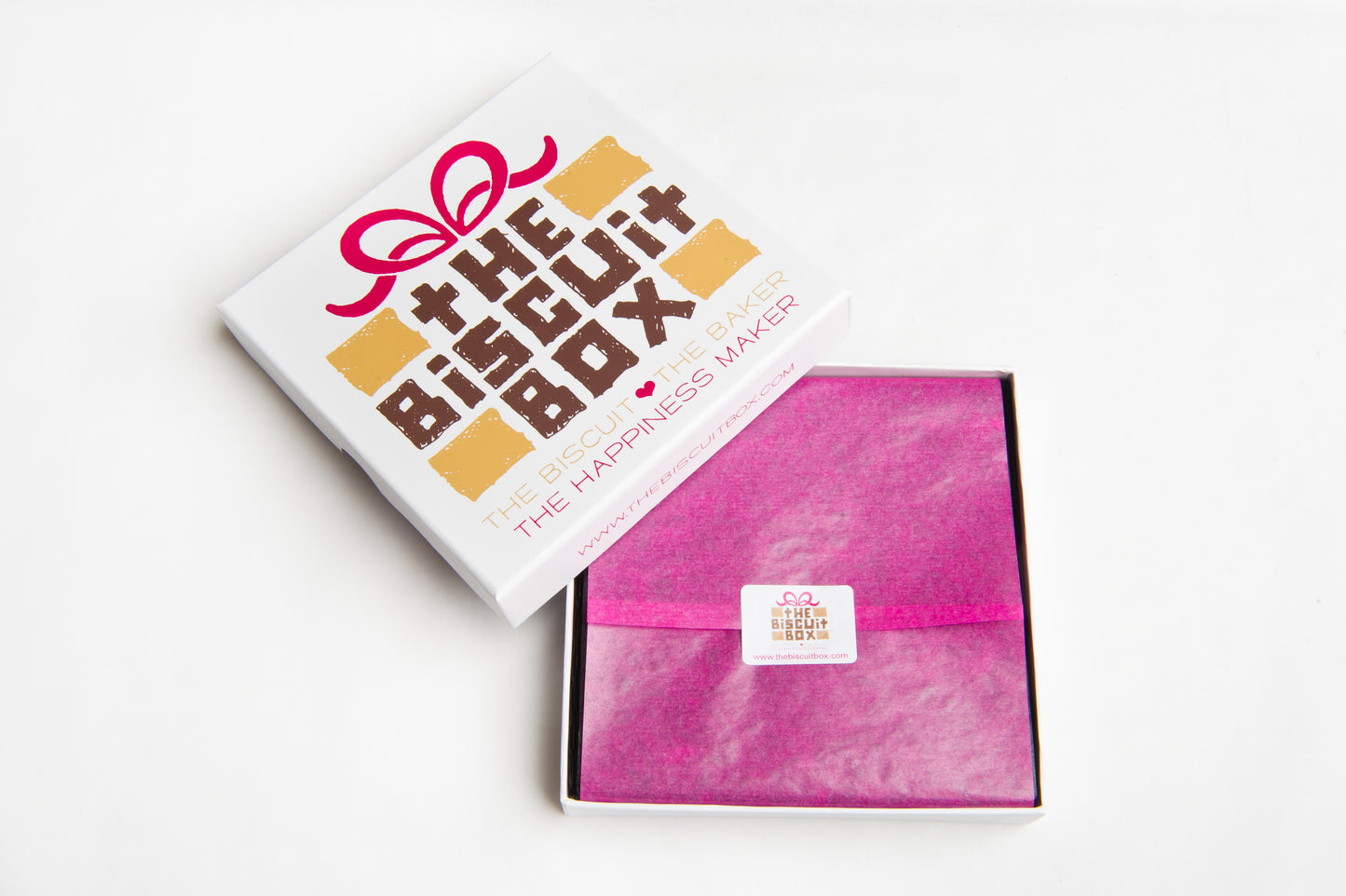 image to show biscuit card packaging. branded lid with pink tissue paper and branded sticker. Small box to fit through letter box so biscuits can be sent by post.