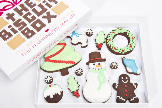 a selection of Christmas biscuits in a shallow box that can be posted. Cookies include Christmas tree, snowman, wreath, holly and Christmas pudding. Luxury iced chocolate biscuit for Christmas gift.