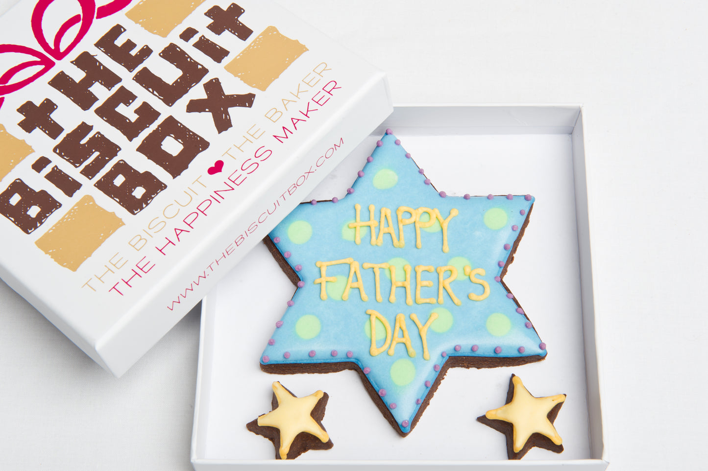 blue star biscuit with the words Happy Fathers Day iced onto it in yellow icing. Two mini yellow stars all displayed in small box.