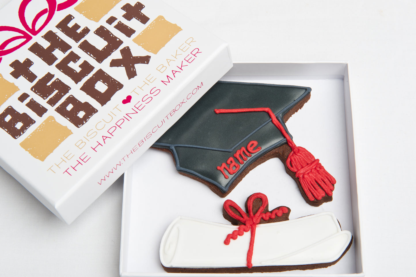 Graduation biscuit gift box. Scroll biscuit and graduate hat with personalised name in red icing.